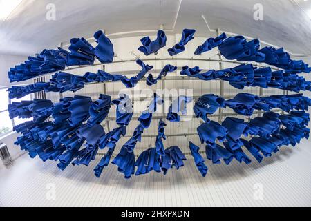 blue workers clothes hanging at the ceiling in a mining plant Stock Photo
