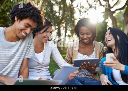 College diversity. Shot of a diverse group of college students sitting outside using digital tablet. Stock Photo