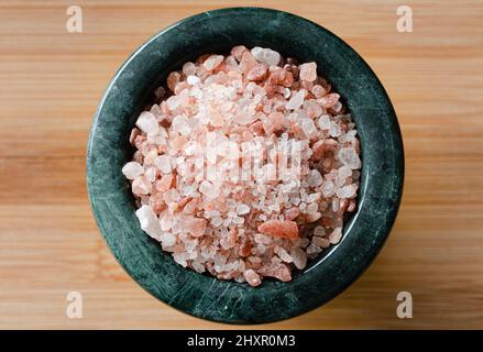 Top view of pink salt in green bowl on wood table Stock Photo