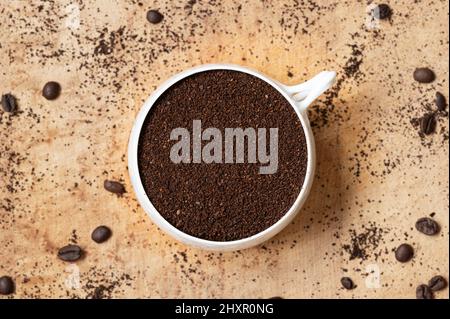 Top view of white coffee cup filled with coffee grounds on wood background Stock Photo