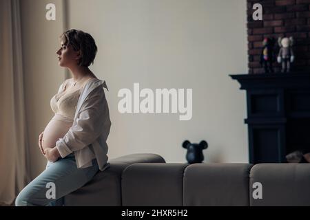 Pregnant woman in jeans and bra feeling sick, isolated on white