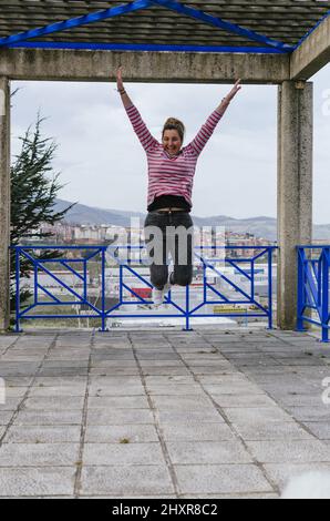 young beautiful brown haired caucasian woman jumping on the stre Stock Photo