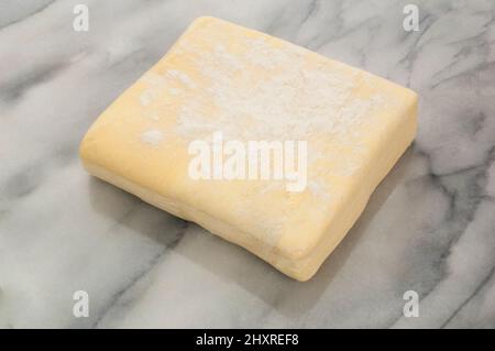 Studio shot of a block of uncooked puff pastry on a marble table - John Gollop Stock Photo