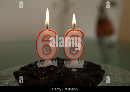 Closeup of a birthday cake with burning candle number 66 Stock Photo