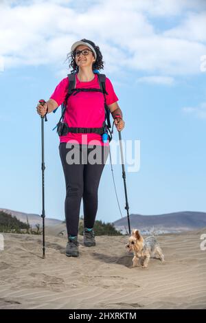 Traveling woman with dog on sandy beach Stock Photo