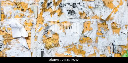 Billboard With Torn Peeled Poster Abstract Background. Outdoor Bulletin Board Or Plywood Panel With Worn Advertising Message, Notice And Stickers Stock Photo