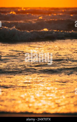 Sea water surface at sunset. Natural sunset warm colors of ocean. Sea ocean water surface with foaming small waves at sunset. Evening sunlight Stock Photo