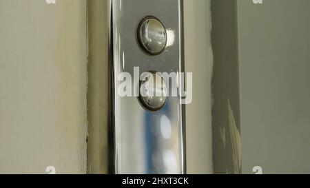 Elevator button and a beige wall. HDR. Close up of metal buttons of a public elevator aat the shopping center. Stock Photo