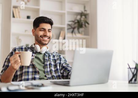 Arab man using laptop drinking coffee office Stock Photo