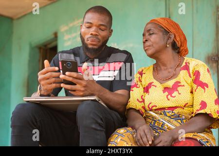Young black male teaching his older mother how to use technology Stock Photo