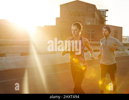 Taking the lead. Shot of two friends out jogging in the city in the early morning. Stock Photo