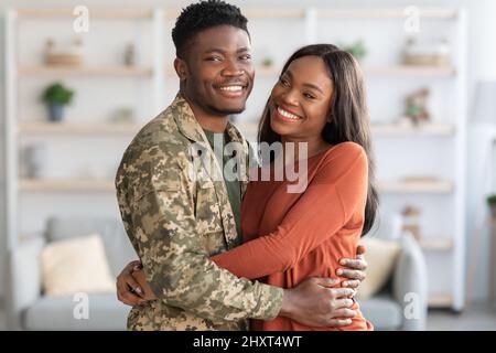 Portrait Of Young African American Male Soldier And Wife Hugging At Home Stock Photo