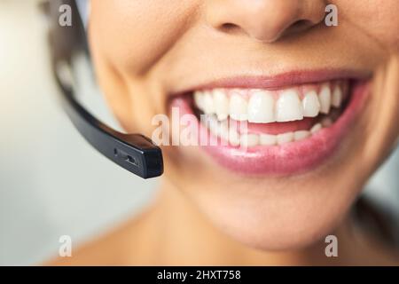 Big smiles when helping the customer. Closeup shot of an unrecognizable female customer support agent smiling in the office. Stock Photo