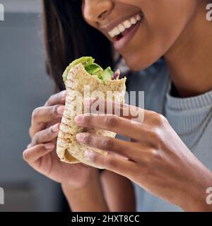 Being healthy has never been so delicious. Shot of a woman enjoying a wrap. Stock Photo