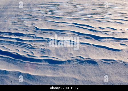 Light and shadow across waves of snow Stock Photo