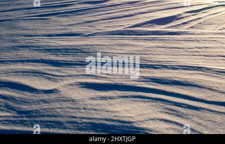 Light and shadow across waves of snow Stock Photo