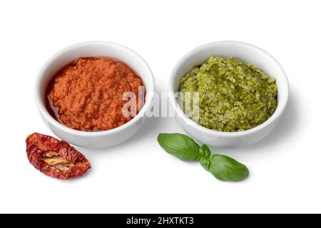 White bowls with red and green Italian pesto close up isolated on white background Stock Photo