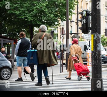 PARIS, FRANCE - JUNE 14, 2018: Parisians. Urban scene. Old ladies and young men crossing the street. Stock Photo