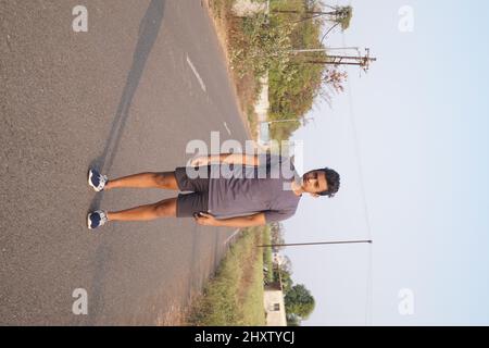 Vertical shot of the young man standing on the road. Stock Photo