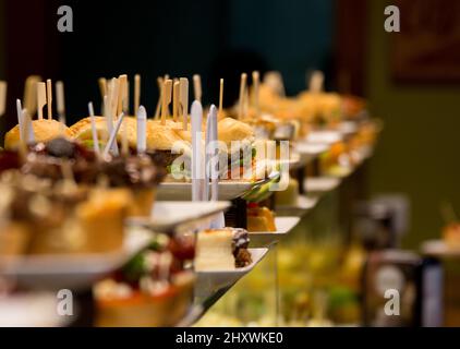 Closeup of the pinchos with wooden sticks on top. Catering products on the plates. Stock Photo