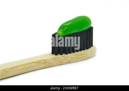 Bamboo toothbrush with green mint toothpaste isolated on white background. Personal oral hygiene concept. Stock Photo
