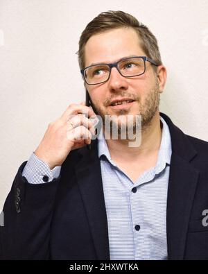 Caucasian unshaven business man in glasses talking on the smartphone and looking away from the camera. Isolated on white background Stock Photo