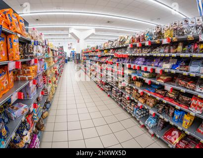 Fossano, Italy - March 12, 2022: aisle with shelves of confectionery products in the MERCATÒ supermarket of the Italian group Dimar associated with Se Stock Photo