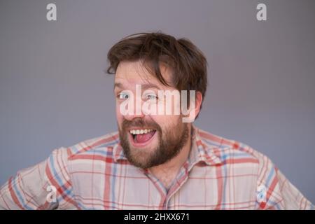 Happy young bearded guy looking at camera, brightfully smiling with teeth, being happy Stock Photo