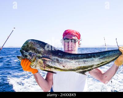 Fisherman with Mahi Mahi in tropical sea Stock Photo