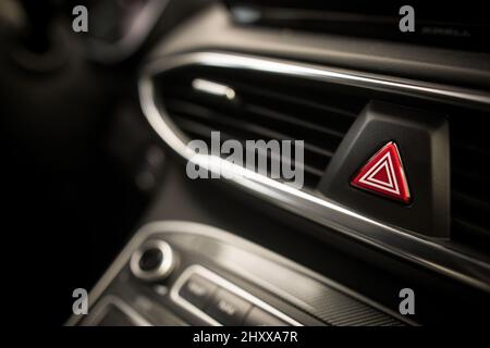 Emergency triangle button on black car dashboard Stock Photo