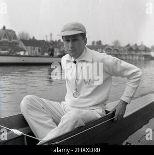 1961, historical, sitting in a rowing boat on the water, the coxswain or cox of the Cambridge University Boat team, R. T. Weston of Selwyn college, with cap and stopwatch. The initals RTW are embrodied on his cotton tracksuit top. Roger Weston had also been the Cambridge cox the previous year. The Oxford & Cambridge Boat Race, the famous university rowing race, first took place 1829 and is an annaul event on the River Thames over the championship course between Putney and Barnes in South West London. Stock Photo