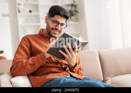 Young Arab man in glasses reading book Stock Photo