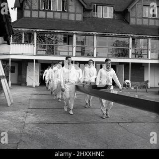 1961, historical, the crew of the Cambridge University Boat club carrying their long rowing vessel out of the boat yard of the Leander Club, for a training session for the upcoming Oxford and Cambridge Boat Race. A famous university rowing race began in 1829 and an annual event on the River Thames, it takes place over the championship course between Putney and Barnes in South West London. Founded in 1818 and one of the oldest rowing clubs in the world, the Leander Club built their clubhouse at Remenham beside the river at Henley-on-Thames in 1897. Stock Photo