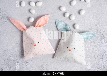 Two bag of sweets in shape of Easter bunny with blue and pink ears on light gray background. Packing of cotton fabric in form of cute bunnys or Stock Photo