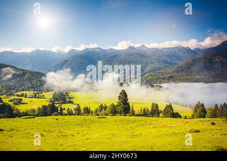 Fantastic panorama of foggy valleys in the Triglav national park. Located in the Bohinj Valley of the Julian Alps. Sky glowing by sunlight. Dramatic u Stock Photo