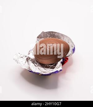 Close up of an unwrapped Cadbury Crème Egg on its foil packaging isolated on a plain white background Stock Photo