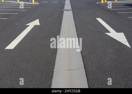 Closeup of two white arrow pointing in opposite directions on car park asphalt road Stock Photo