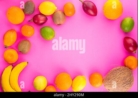 Citrus fruits on rose background. Assorted citrus fruits and tamarillo. Kiwi on pink table and other fruits. Copy space for your text. Fruits on circl Stock Photo