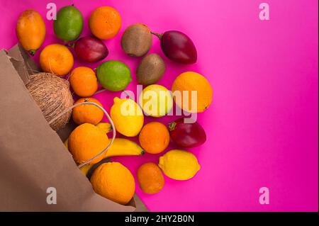 Citrus fruits on rose background. Assorted citrus fruits and tamarillo. Kiwi on pink table and other fruits. Copy space for your text. Fruits from pap Stock Photo