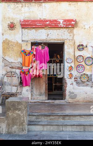 Loreto, Baja California Sur, Mexico. November 17, 2021. Pink and orange blouses outside a store in an old stucco building. Stock Photo