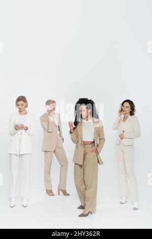 African american businesswoman using cellphone near colleagues in formal wear on grey background,stock image Stock Photo