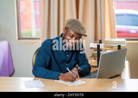 Young Black guy from Ghana working on his desk cheerfully Stock Photo