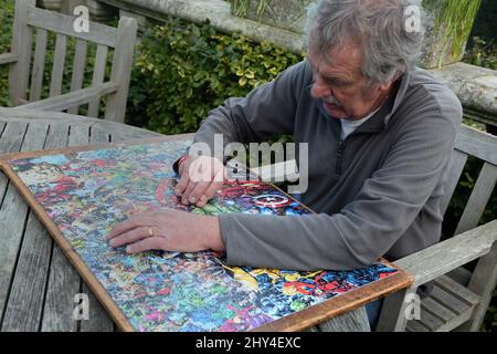 Man Doing a Marvel 1000 Piece Impossible Puzzle in Garden Stock Photo