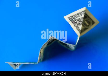 Top view of a dollar banknote money making a rocket origami isolated on a blue background Stock Photo