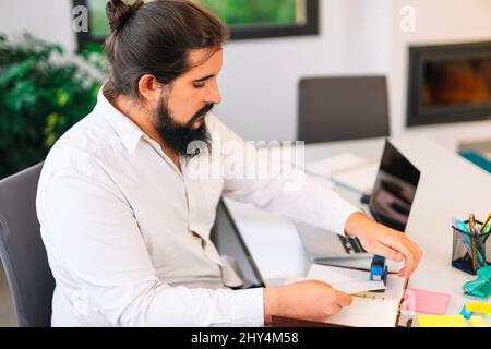 Young entrepreneur stapling papers while working at home.  Stock Photo
