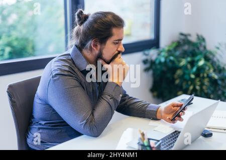 Young entrepreneur concentrating on the mobile phone Stock Photo