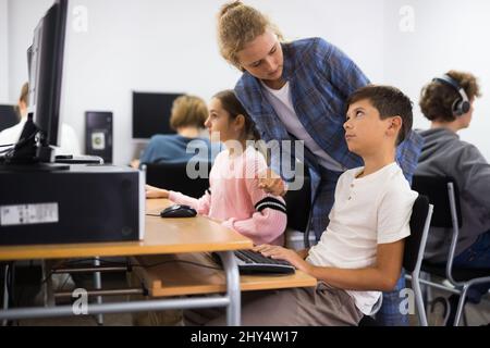 Teacher helping student with computer work Stock Photo