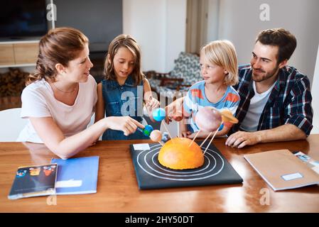 Were starting to think that mom is an alien. Shot of a beautiful young family working together on a science project at home. Stock Photo