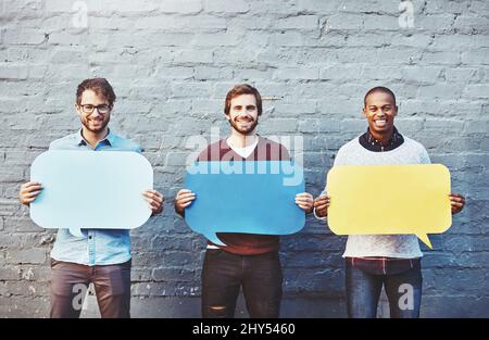 Theyve got some thoughts to share. Portrait of a group of young men holding speech bubbles against a brick wall. Stock Photo