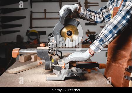 Carpenter using an electric circular saw, cutting piece of wood. High quality photo. Stock Photo